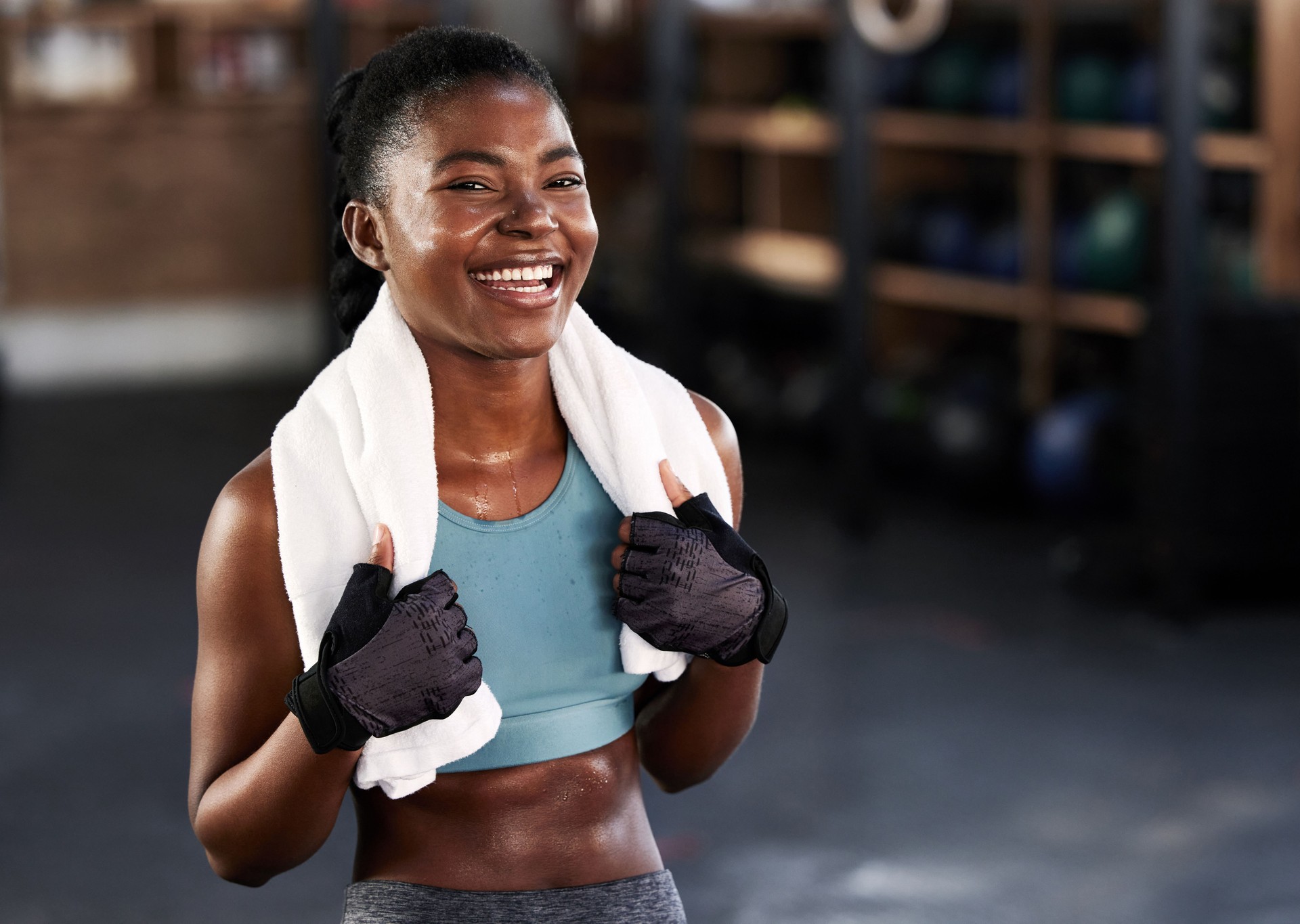 Shot of a sporty young woman posing with a towel around her neck at gym